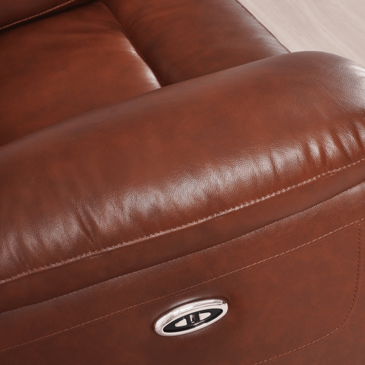 Close-up of a brown leather recliner with a visible brand logo.
