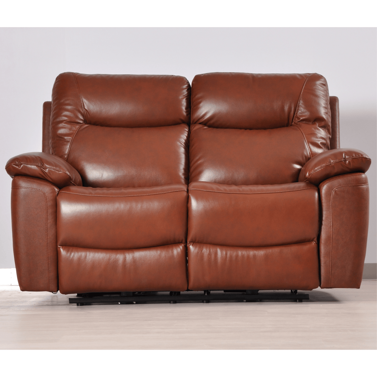 Brown leather reclining sofa on a light wooden floor with a white wall background